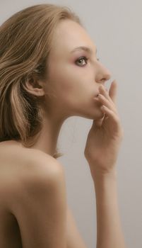 Profile of a woman with blonde hair in a thoughtful pose against a neutral background.