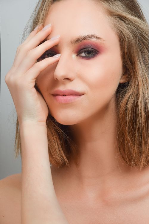 Free Close-up portrait of a woman with striking eyeshadow and a gentle expression. Stock Photo