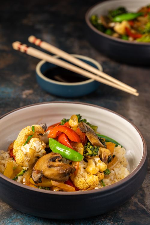 Free Vibrant Asian stir-fry with fresh vegetables and rice in a ceramic bowl. Stock Photo