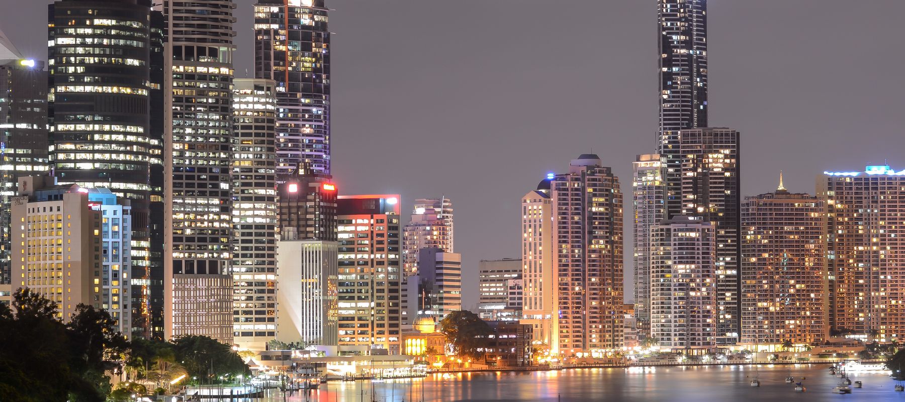 A breathtaking view of Brisbane's illuminated skyline at night with reflections on the river.