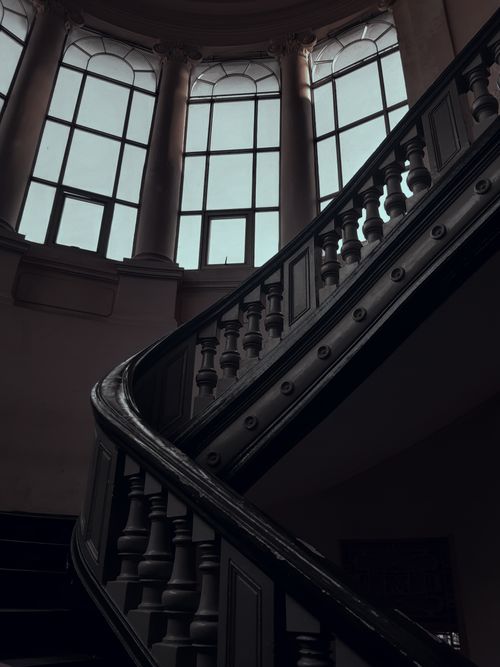 Free A low angle view of an ornate spiral staircase leading to large windows in a historic building. Stock Photo