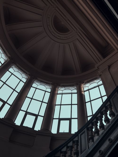 Free Low-angle shot of a dome ceiling with ornate design, showcasing large arched windows. Stock Photo