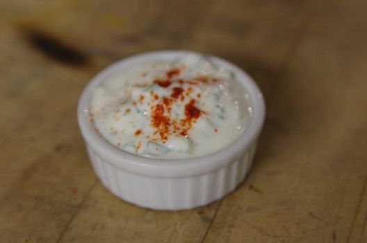 A vibrant creamy yogurt dip in a white ramekin, garnished with paprika.