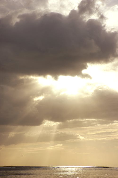 Sunlight behind Clouds on Sky over Sea
