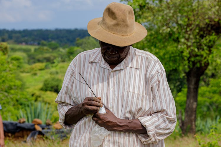 Elderly Man In Hat Working In Garden