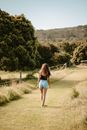 Girl with Curly Hair Walking on Road along Trees