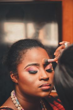 A beautiful portrait of a woman getting her makeup applied with a brush.