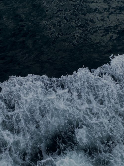 Free A dramatic capture of ocean waves splashing against the sea, viewed from above, showcasing dark turbulent waters. Stock Photo