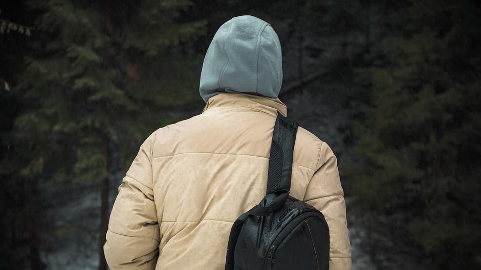 Marcheur avec sac à dos et veste à capuche dans une forêt humide, photographie d’illustration