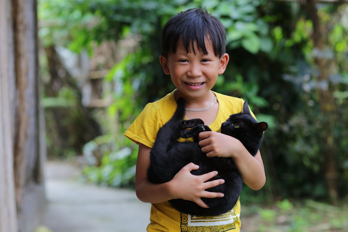 Free Boy in Yellow Crew Neck T-shirt Carrying Black Cat Stock Photo