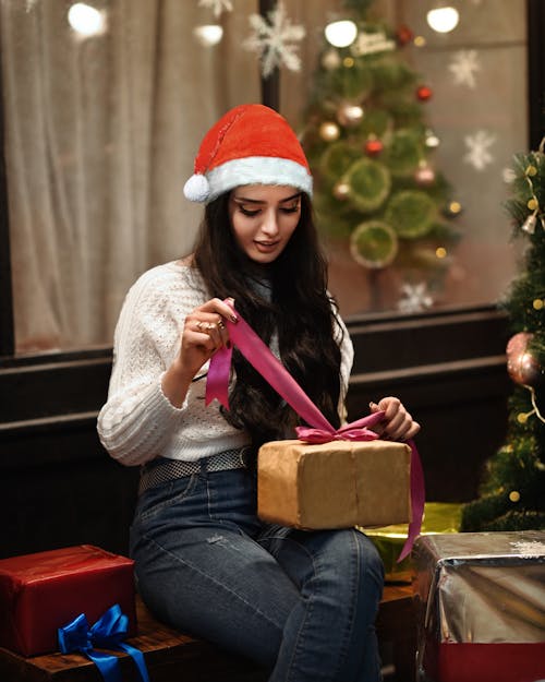 Woman in Santa Hat Unwrapping Christmas Gift