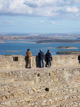 Tourists enjoy a scenic view of the Alqueva Reservoir from the ancient ruins in Évora, Portugal.