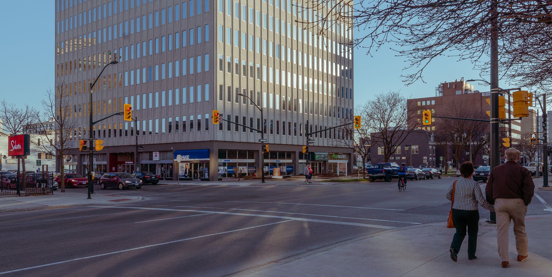 Busy street scene at an urban intersection in downtown London, Canada with pedestrians and cars.