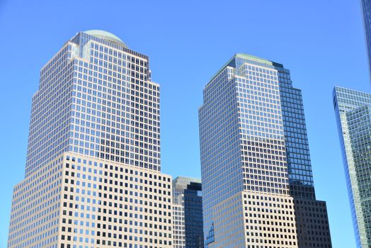 Stunning low-angle view of modern skyscrapers in downtown New York under a clear blue sky.