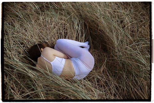 Woman Laying Curled Up in Hay 