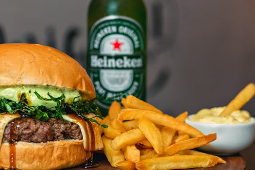 Close-up of a gourmet burger with fries and a bottle of Heineken beer.