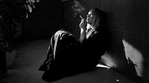 Free Woman Wearing a Dress Sitting on the Floor Smoking Cigarette Stock Photo