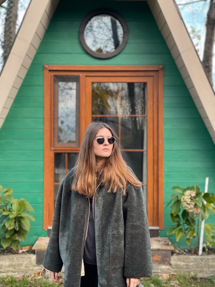 Woman In Coat Posing Near House