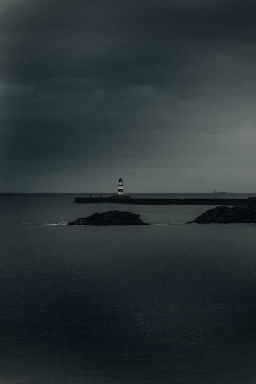 Lighthouse on Coastline under Overcast Sky