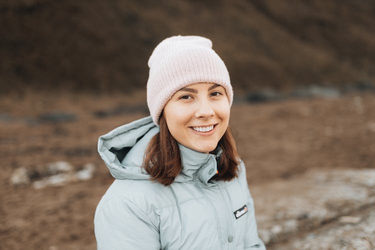 Woman In Sports Jacket And Hat Smiling At Camera