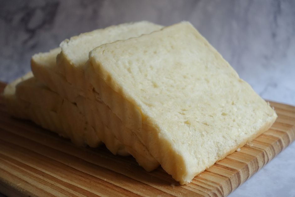 Close-up of freshly sliced white bread arranged on a wooden chopping board, perfect for culinary presentations.