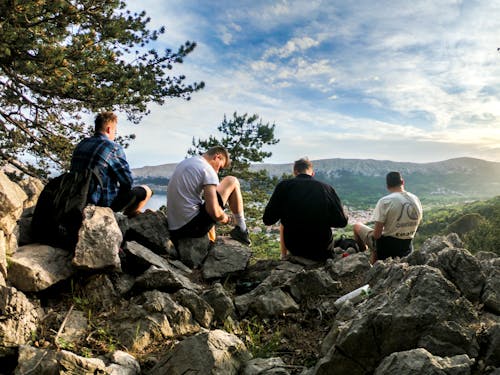 Four Men Seated on Rocks Facing Mountain