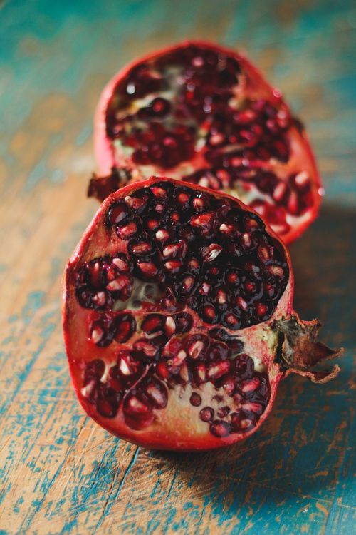 Free A fresh pomegranate cut in half, showcasing its vibrant seeds on a rustic wooden surface. Stock Photo
