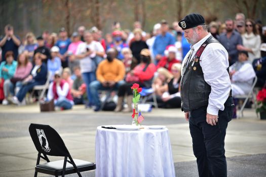 A veteran stands solemnly at a memorial ceremony honoring fallen soldiers at Fort Bragg, NC.