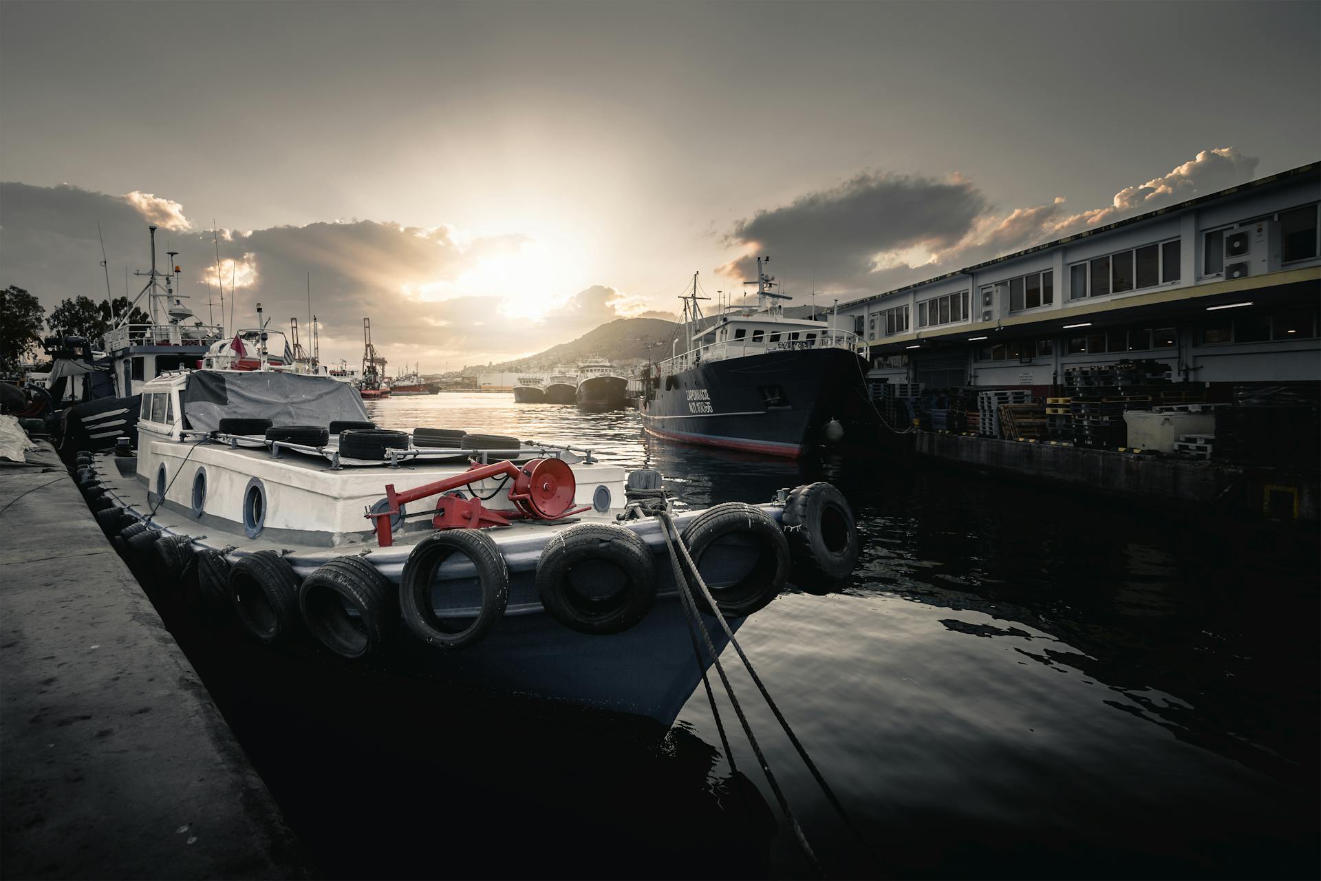 Scenic view of boats moored at a harbor during sunset with dramatic lighting.