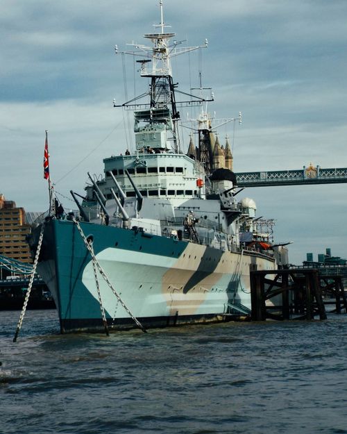 Free Historic HMS Belfast docked on the River Thames with iconic London backdrop. Stock Photo