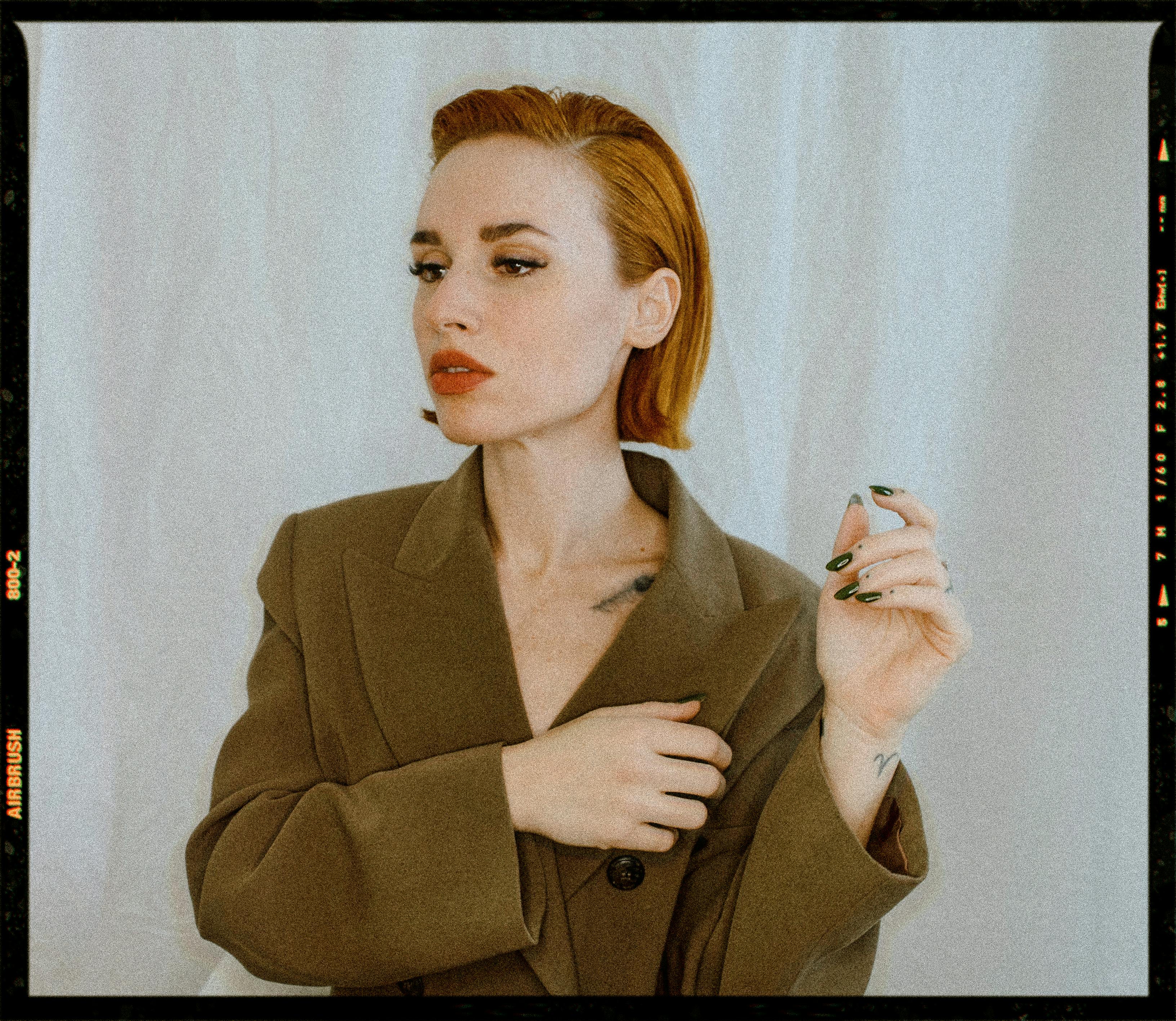 Studio portrait of a woman in a stylish olive coat showcasing elegance and glamour.