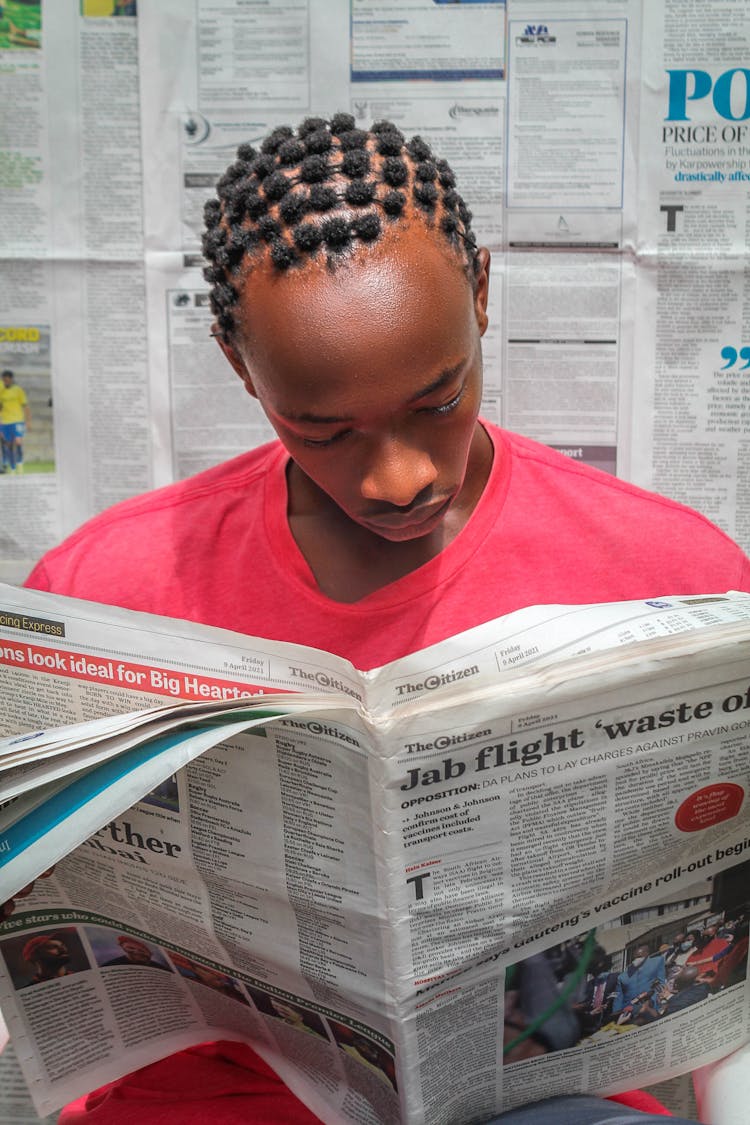 Teenager Boy In Pink Shirt Reading Newspaper