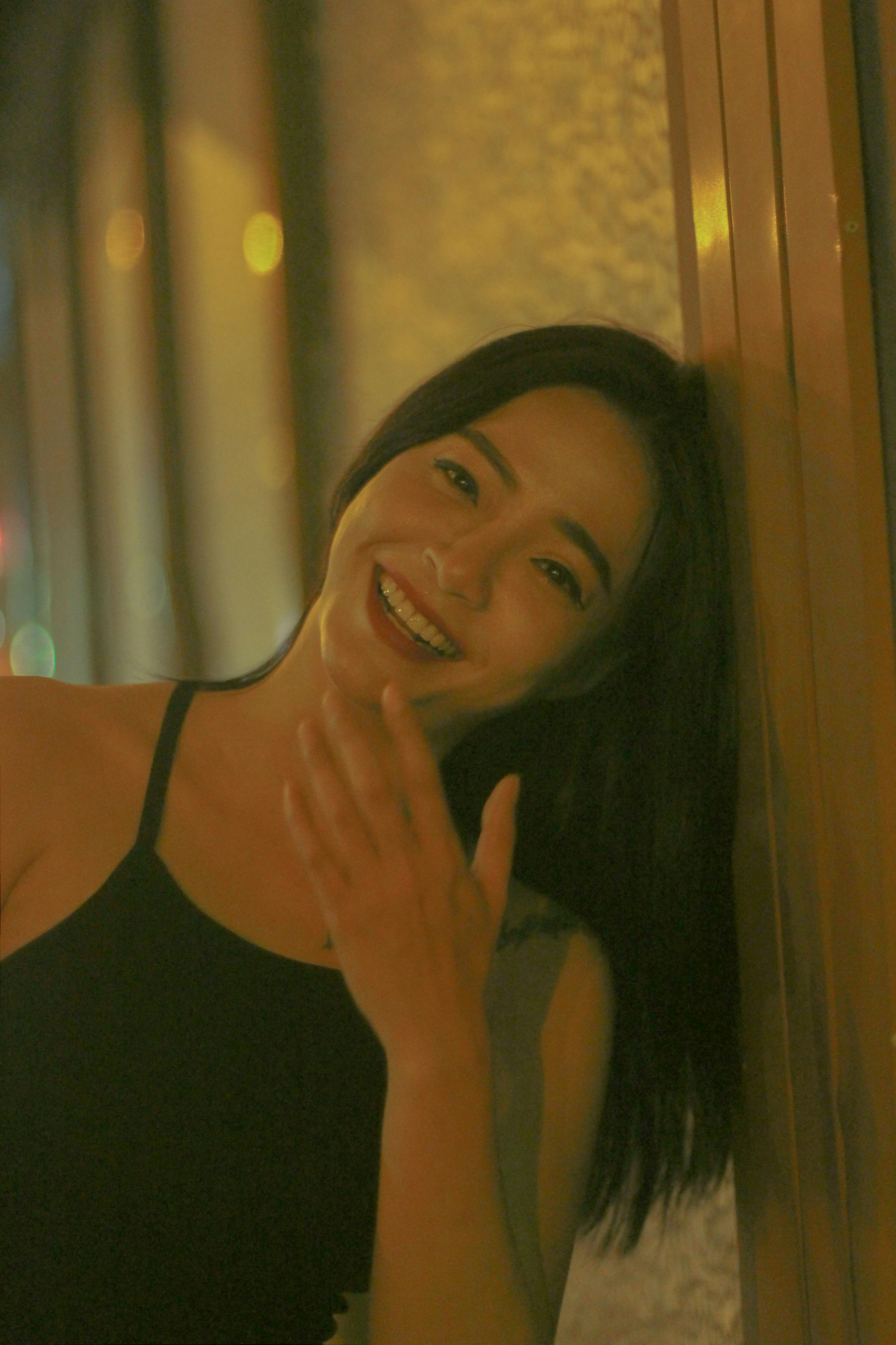 A candid portrait of a woman laughing while leaning against a wall at night, exuding joy and elegance.