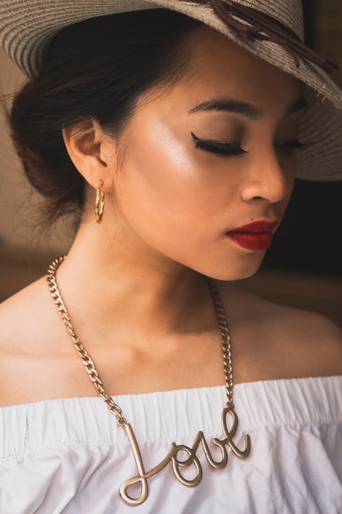 Woman Wearing a Hat and Gold Necklace