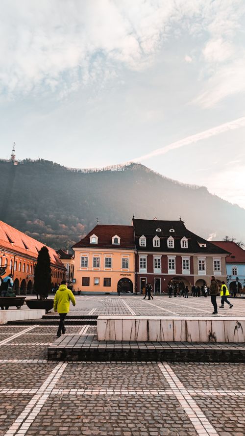 Free Idyllic scene of a European town square with historic architecture and scenic mountain backdrop. Stock Photo