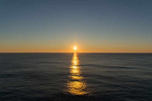Free Serene ocean sunset with vibrant hues and golden reflections on the water. Stock Photo