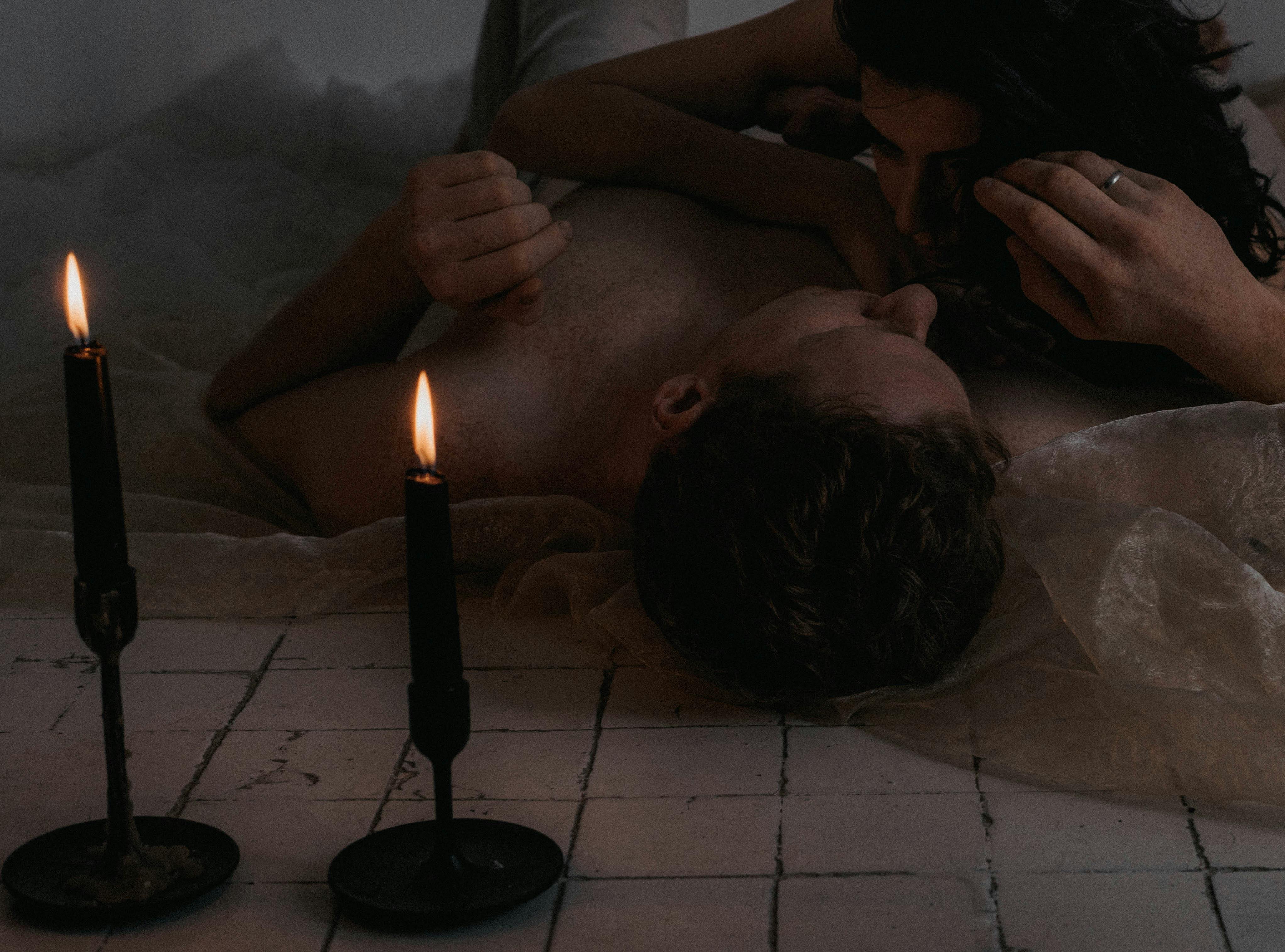 Romantic couple lying together on floor surrounded by flickering candles, creating cozy intimate atmosphere