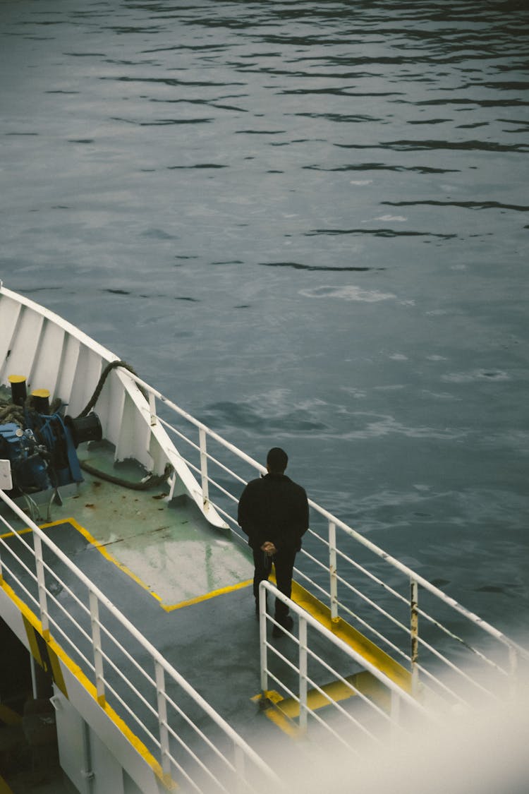 Man Standing On Bow Of Motorboat And Looking At Water