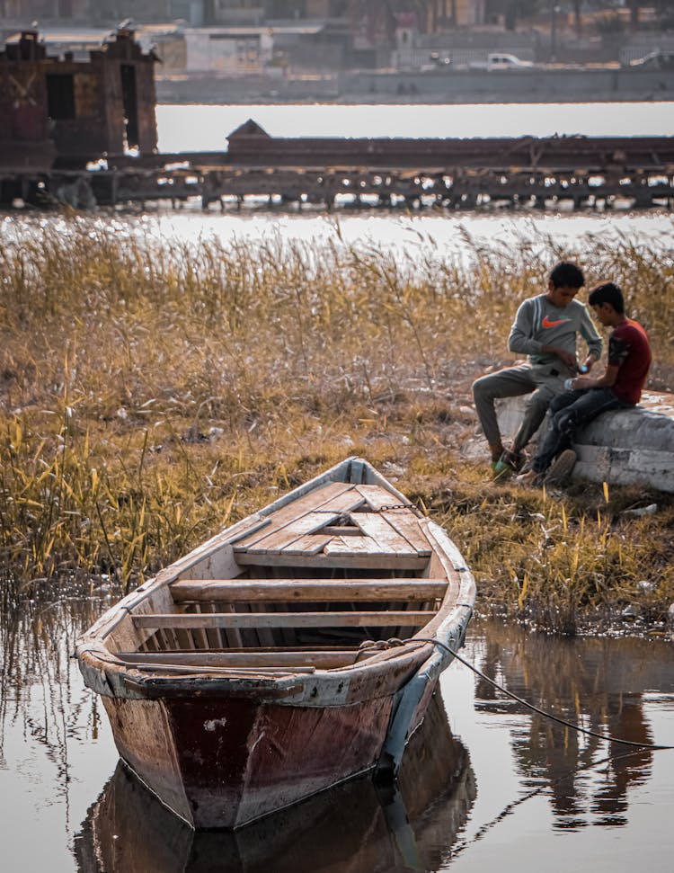 Teenagers And Boat On Riverbank