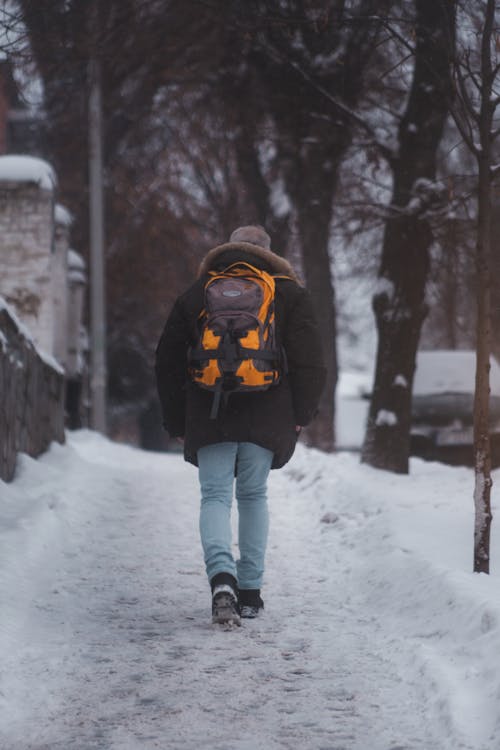 Person Carrying Backpack Walking on Sidewalk