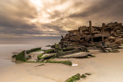 Weathered ruins on a sandy Brazilian beach under dramatic cloudy skies at sunset.