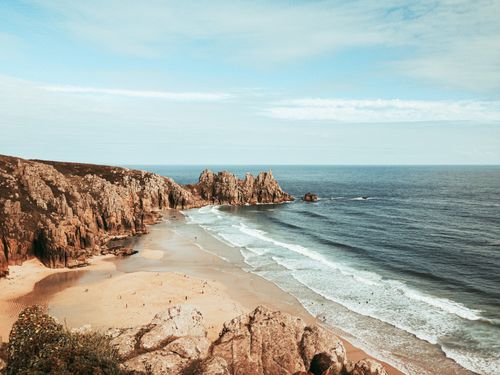Free Beautiful beach in England with rocky cliffs and serene waves under a cloudy sky. Stock Photo