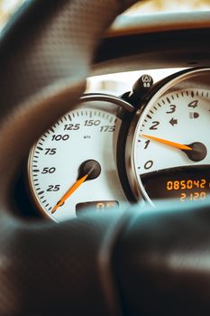 Close-up view of a car's speedometer and dials in focus, showcasing speed and revolutions.
