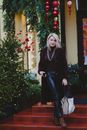 Woman in Black Long Sleeve Shirt and Black Pants Standing Beside Green Christmas Tree