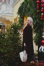 Woman in Black Long Sleeve Shirt Standing Near Green Christmas Tree