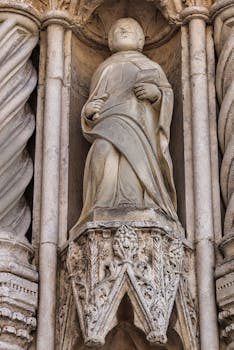 Close-up view of a stone statue on a historic gothic facade. Intricate details and craftsmanship.