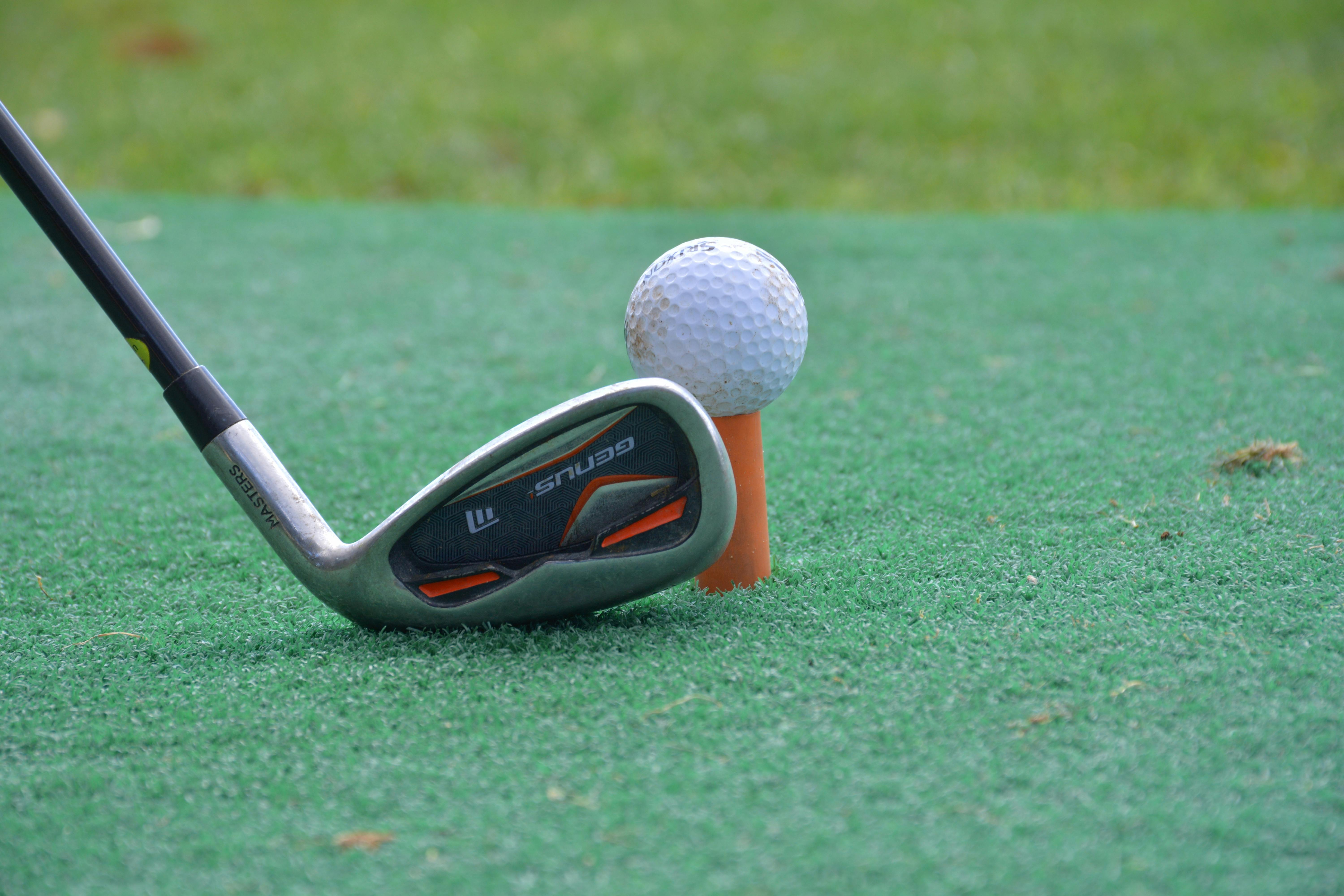 a golf ball on a tee near the putter