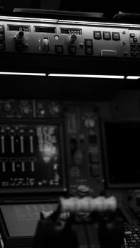 Close-up view of an aircraft cockpit control panel in monochrome, highlighting buttons and levers.