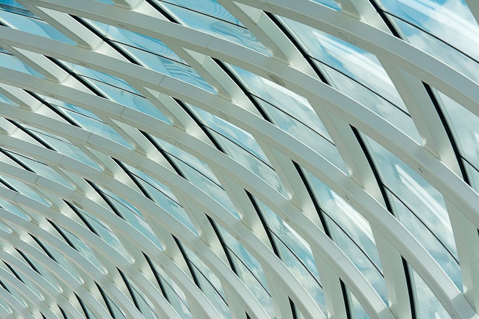 Abstract view of a modern glass and steel ceiling with geometric design and natural light.
