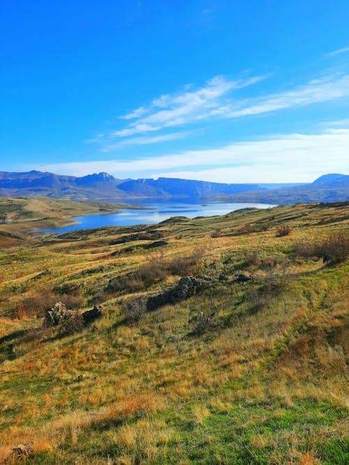 Green Grass Field Near Mountains Under Blue Sky